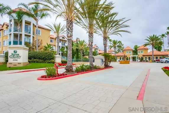 Front view of a multi-story apartment complex with palm trees and landscaped entrance.