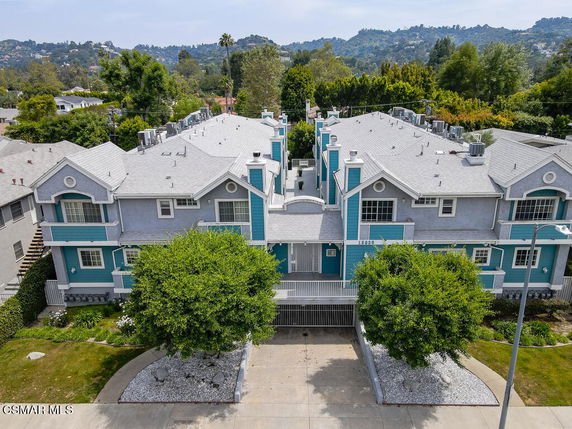 Front view of a two-story apartment building with a grey and teal exterior and a gabled roof.