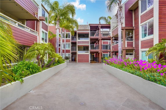Front view of a multi-story building with balconies and tall palm trees.