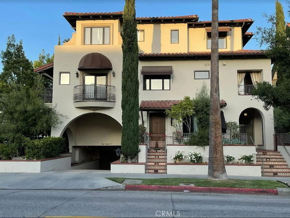 Front view of a multi-story house with arched entryways and a balcony.