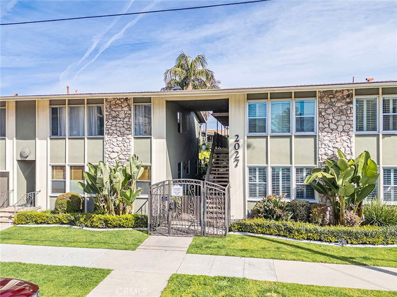 Front view of a two-story apartment building with large windows and a central staircase entrance.