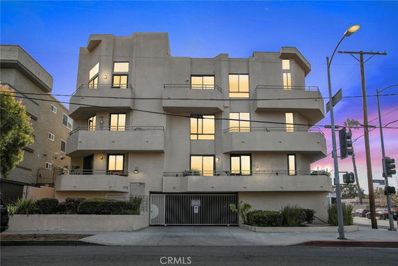 Front view of a multi-story building with balconies and a gated entrance at street level.