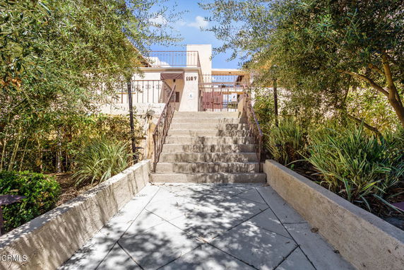 Front entrance view of a building with stairs leading up to a gate.