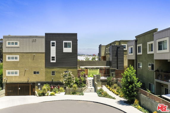 Front view of a modern multi-story apartment complex with a gated entrance.