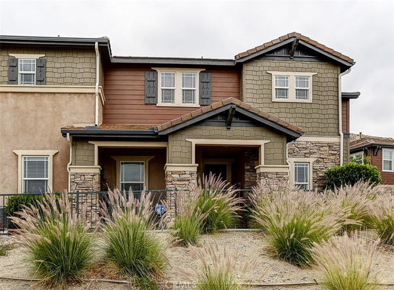 Front view of a two-story house with a mix of stone and wood exterior.