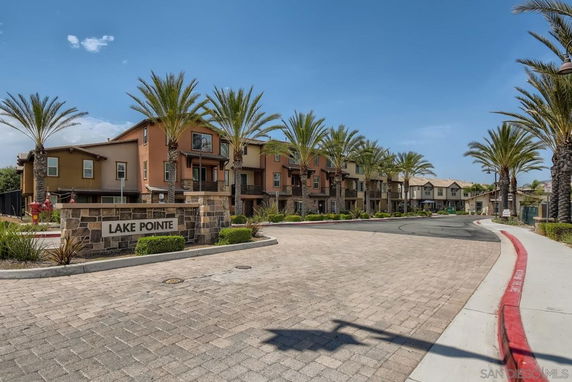 Front view of a housing complex with multiple two-story buildings and palm trees.