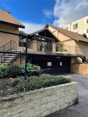 Front view of a multi-story building with an external staircase and entrance.