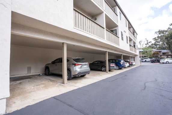 Covered parking area underneath a multi-story building.
