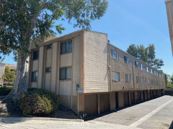 Front view of a three-story apartment building with a covered parking area underneath.