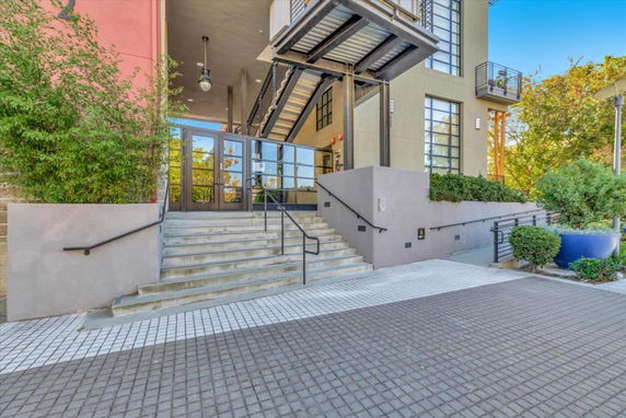 Front view of a multi-story building with glass door entrance and stairs.
