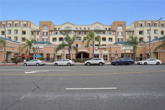 Front view of a multi-story commercial and residential building with shops at the ground level.
