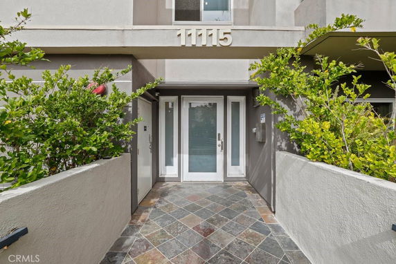 Front view of a modern building entrance with a tiled pathway and glass door.