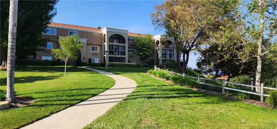 Front view of a multi-story residential building with a garden pathway leading to it.
