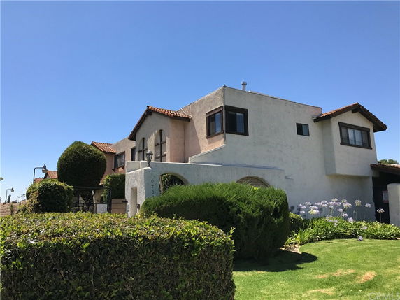Front view of a two-story house with a stucco exterior and terracotta roof tiles.