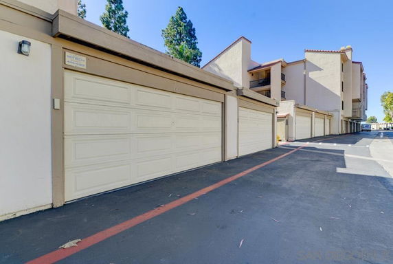 Outdoor parking area with multiple garage doors in a residential building.