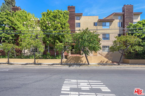 Front view of a multi-story residential building with trees in front.