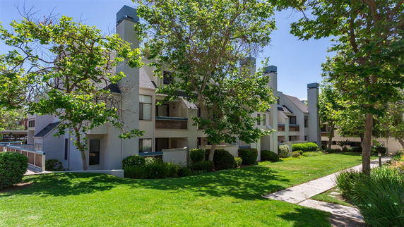 Front view of a multi-story residential building with balconies and trees.