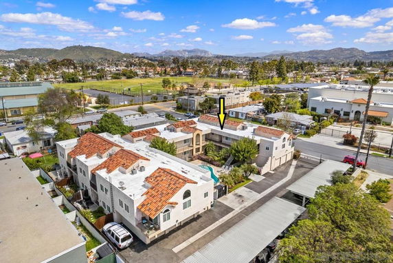Aerial view of residential buildings and surrounding neighborhood with mountains in the background.
