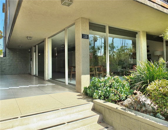 Front view of a building with large glass windows and steps leading to the entrance.