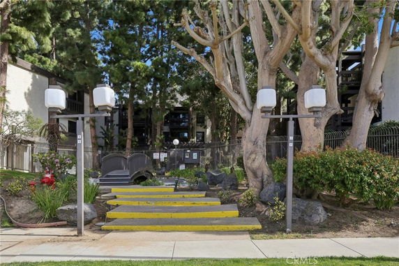 Front view of a multi-story building with a landscaped entrance and outdoor lighting.