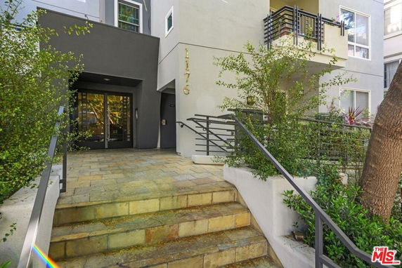Front view of a multi-story building with stairs leading to the entrance.