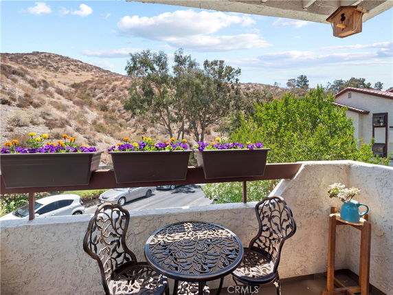 Balcony view with hills and greenery in the background.