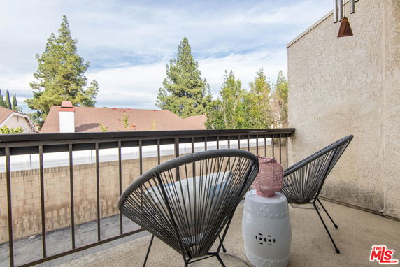 Balcony view with chairs overlooking trees and rooftops.