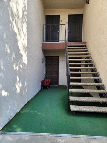 Entrance view of a two-story building with staircase leading to upper floor doors.