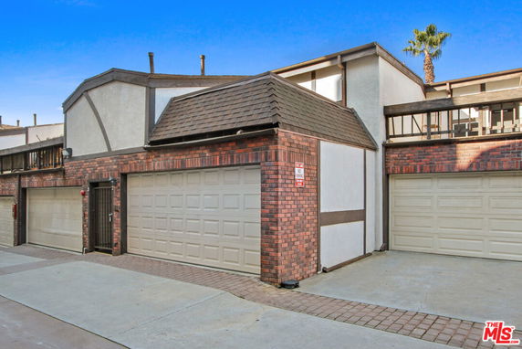 Front view of a multi-level building with brick and paneling facade, including two garages.