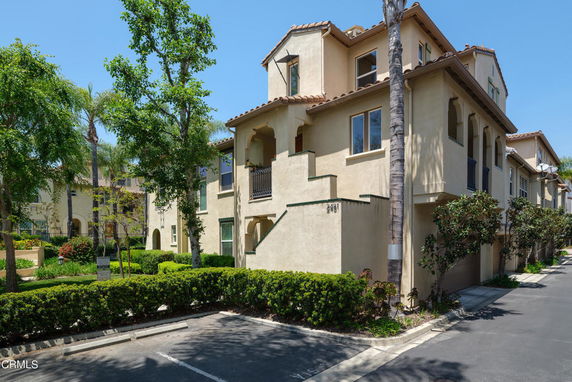 Front view of a multi-story building with a stucco exterior and tiled roof.