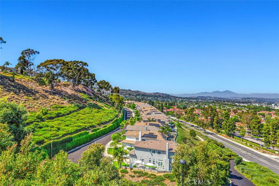 Panoramic view of residential area surrounded by greenery and distant mountains.