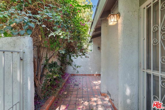 Side view of a house with a tiled walkway and vine-covered wall.