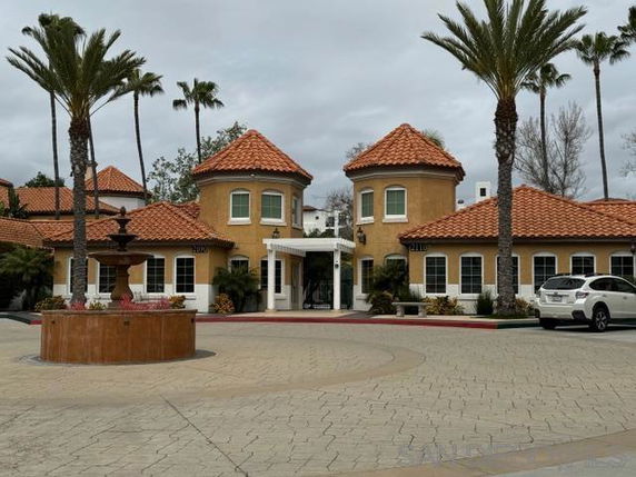 Front view of a building with two round towers and red-tiled roofs.