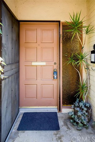 Front view of a house entrance with a tan door and adjacent glass panel.