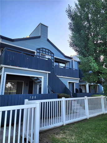 Front view of a multi-story residential building with balconies and blue siding.