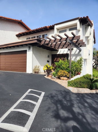Front view of a house with a brown garage door and wooden pergola.