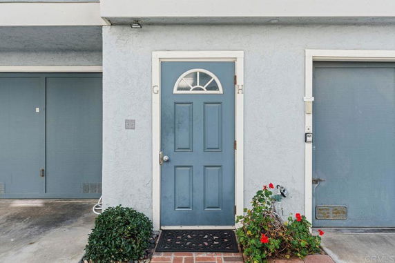 Front view of a house entrance with a blue door and two garage doors.