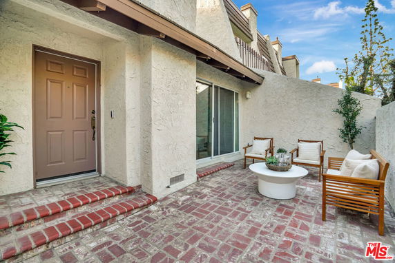 Front view of a house with a patio area featuring brick steps and seating.