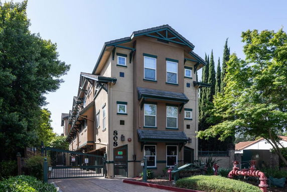 Front view of a multi-story building with decorative trim and gated entrance.