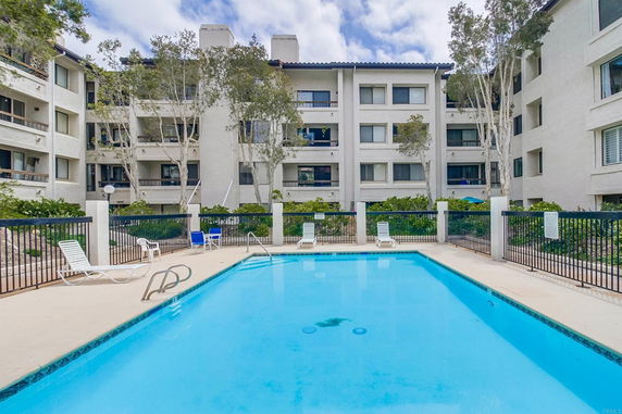 Outdoor swimming pool in front of a multi-story residential building.