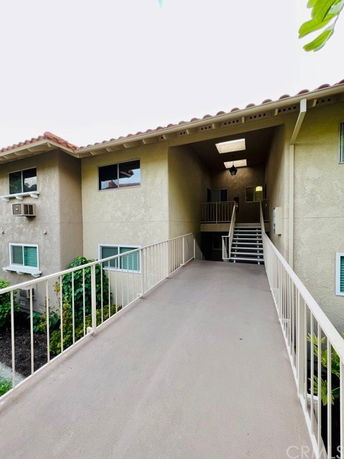 Front view of a multi-story building with a walkway and stairs.