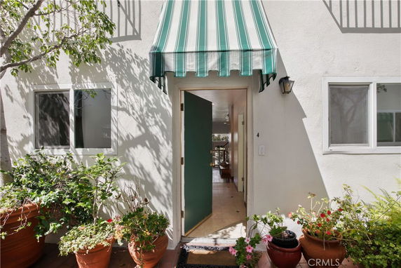 Front entrance of a building with an open door and striped green canopy.
