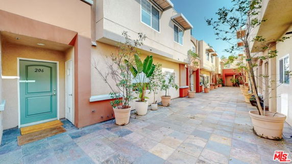 Front view of multi-story building with entrance doors and potted plants.
