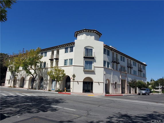 Front view of a multi-story building with balconies and arched entrances.
