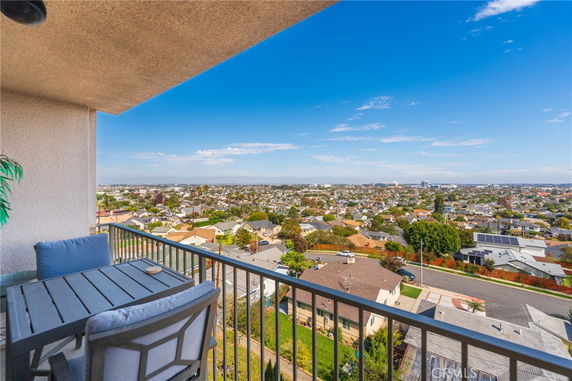 Panoramic view of a cityscape from a balcony with a dining table and chairs.