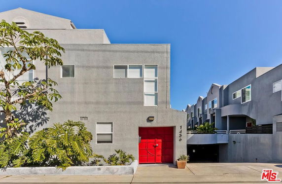 Front view of a modern two-story building with a red garage door.