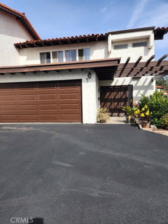 Front view of a house with a two-car garage and wooden pergola.