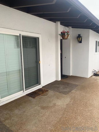 View of a house entrance with sliding glass doors and a small overhang.