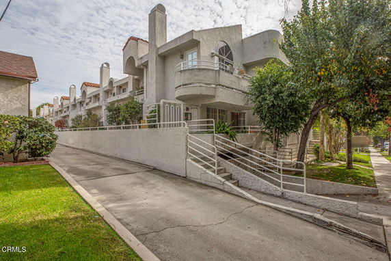 Front view of a multi-story building with balconies and a sloped walkway.