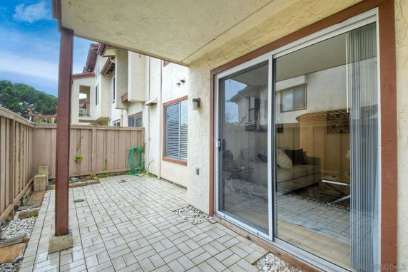 View from a patio area with sliding glass doors, showing neighboring building units.